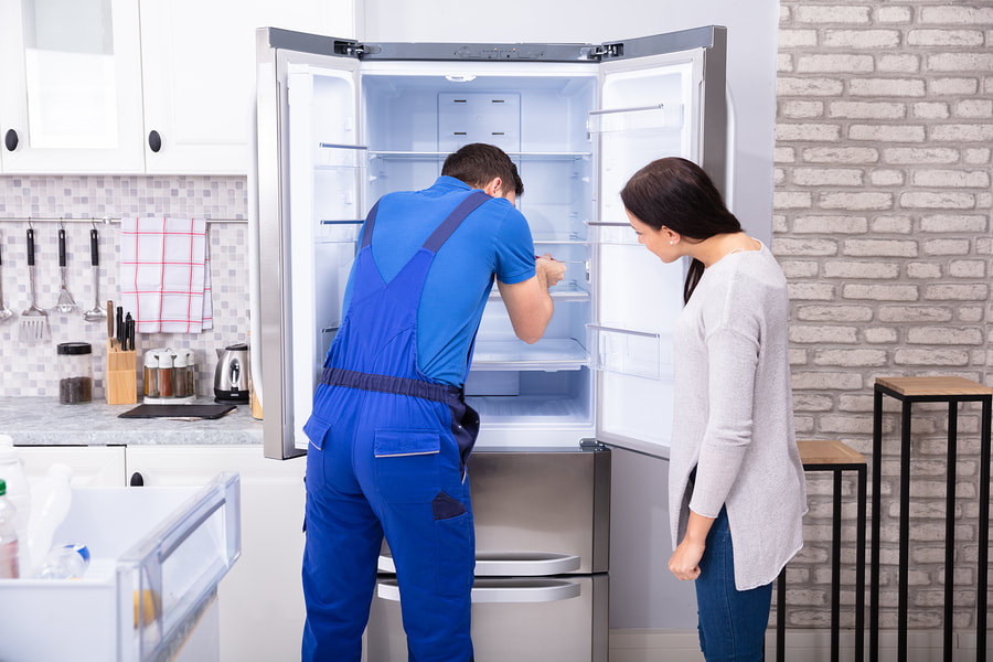 man checking the refrigerator with woman beside him